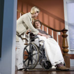 Nurse helping elderly woman in wheelchair at home