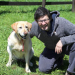 young man with blacks hair smiling with labrador dog