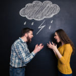 Quarrelling couple standing against background of chalkboard and screaming