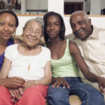 Couple sitting with their teenage daughter and mother in-law on a couch