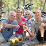 Two older couples enjoying a picnic in the woods